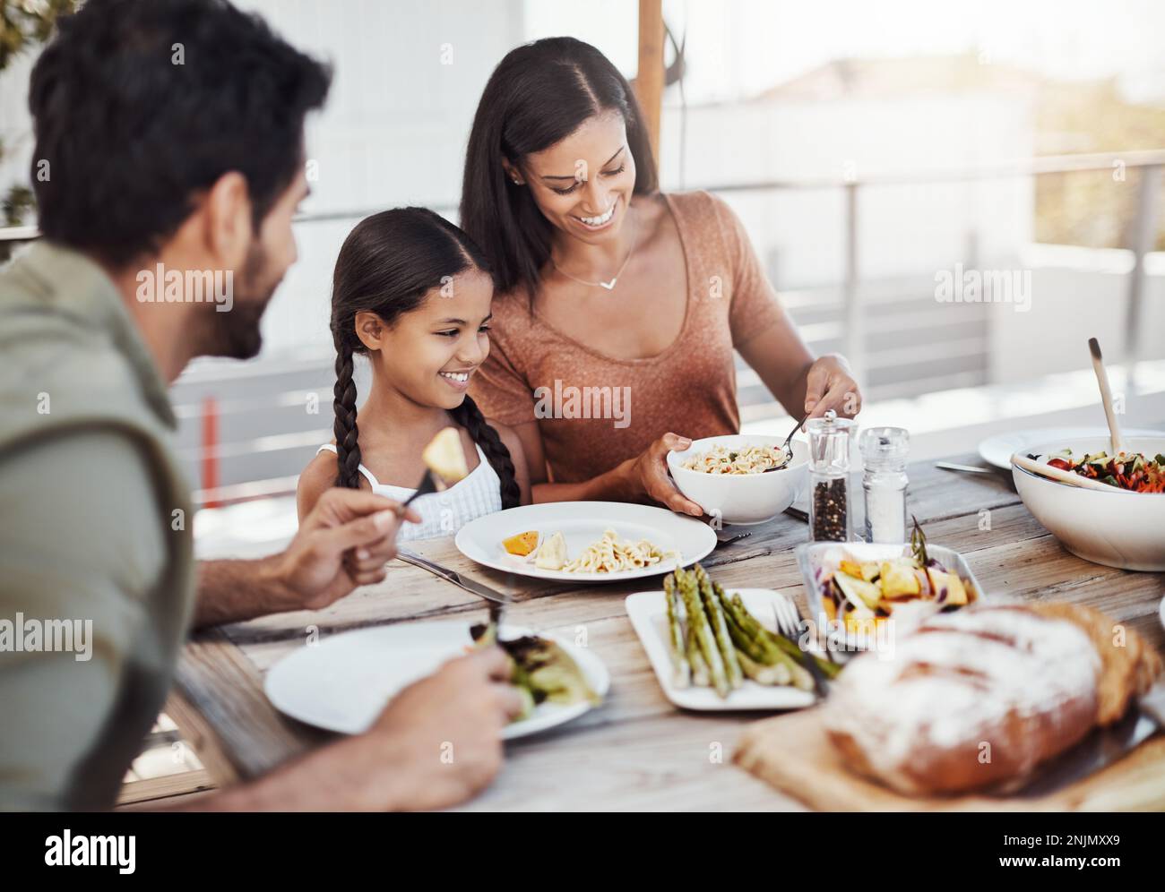 Zeit fürs Essen, Zeit für die Familie. Eine glückliche junge Familie, die gemeinsam im Freien speist. Stockfoto