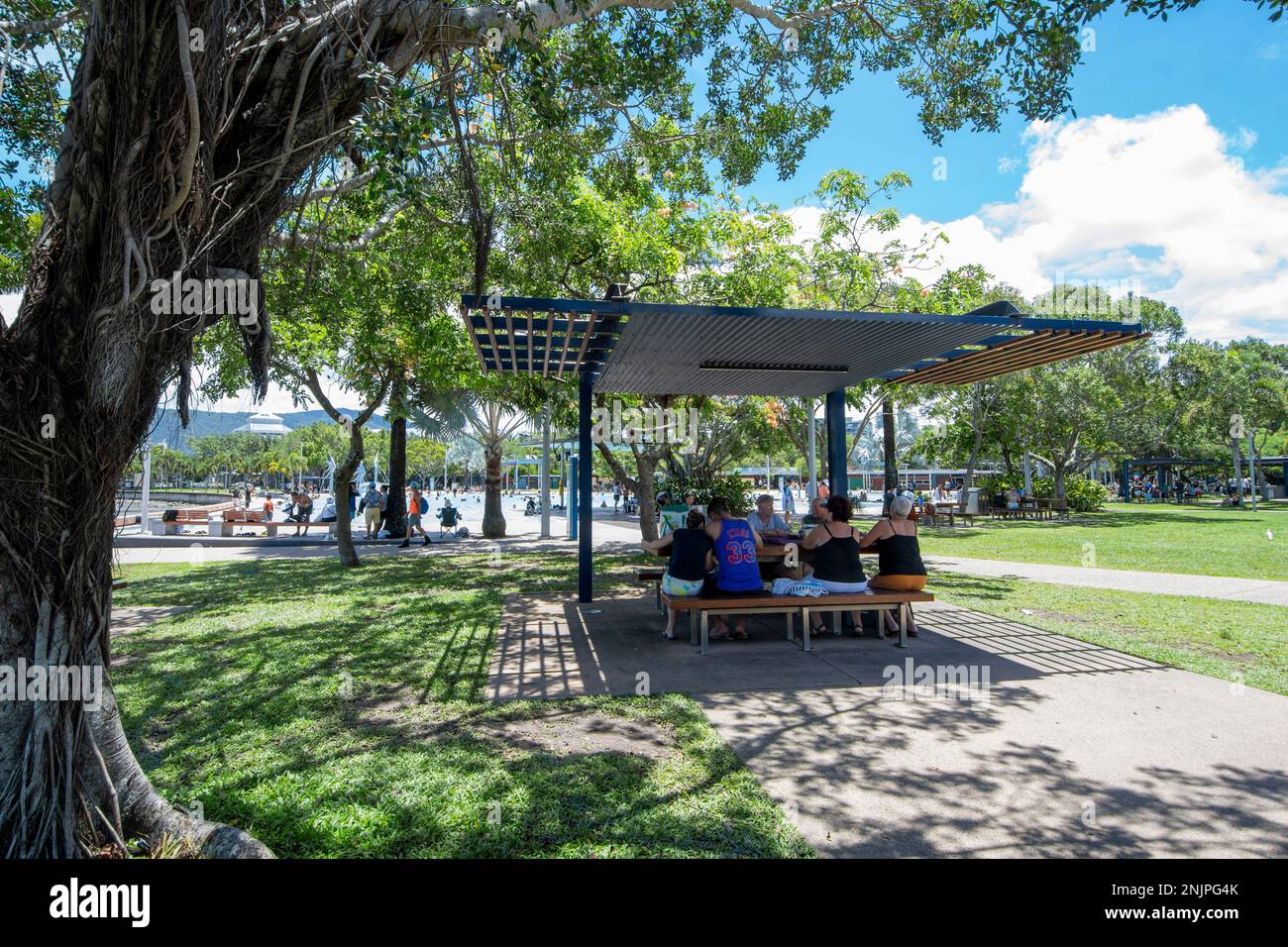Die Leute saßen an einem Tisch im Schatten auf der Cairns Esplanade an einem heißen, sonnigen Tag, Cairns, Far North Queensland, FNQ, QLD, Australien Stockfoto