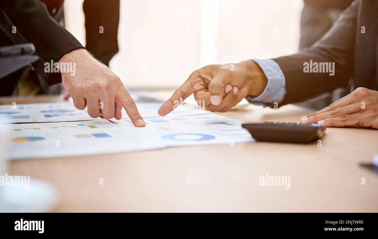 Geschäftsleute zeigen mit dem Finger auf einen Finanzbericht, diskutieren und teilen Ideen, während sie die Finanzstrategie im Meeting analysieren und planen. cr Stockfoto