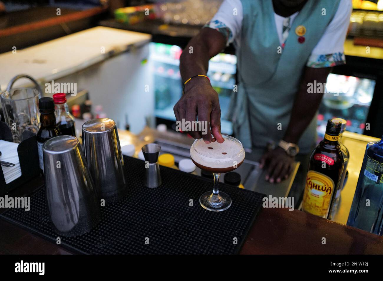 Ein Mixologe streut Kaffeebohnen auf ein Glas Espresso martini in einer
