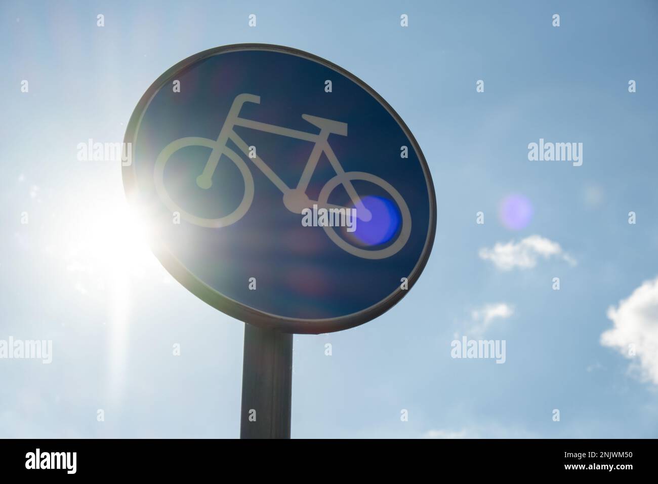 Rundes Straßenschild mit weißem Fahrrad auf blauem Hintergrund, was für  Radfahrer einen obligatorischen Radweg vor blauem Himmel bedeutet. Blaues rundes  Schild am Fahrradweg-Pol. Radweg Stockfotografie - Alamy
