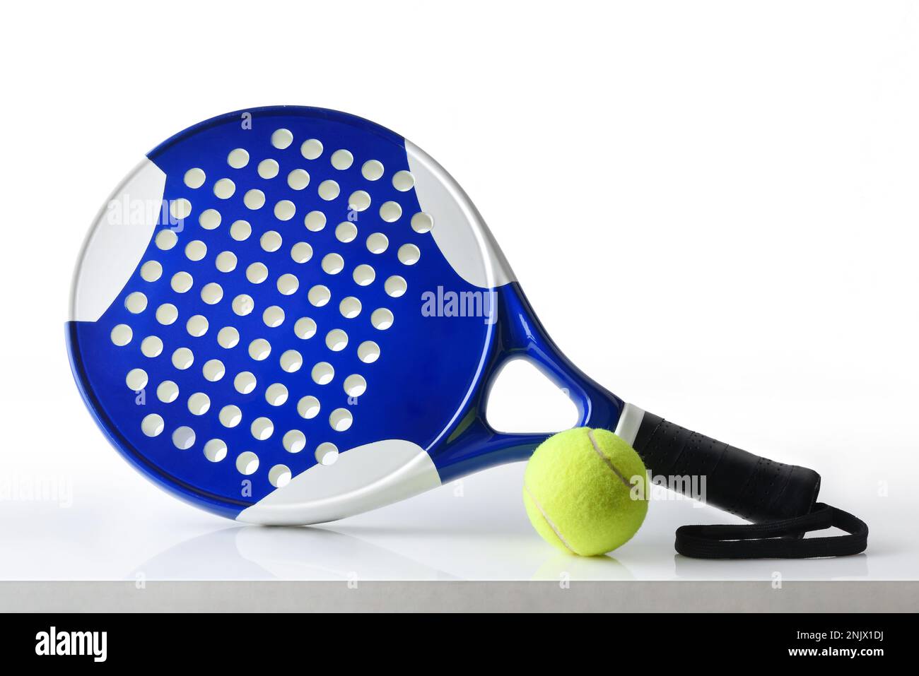 Padel-Schläger und Ball werden auf weißem Tisch und isoliertem weißem Hintergrund reflektiert. Vorderansicht. Stockfoto