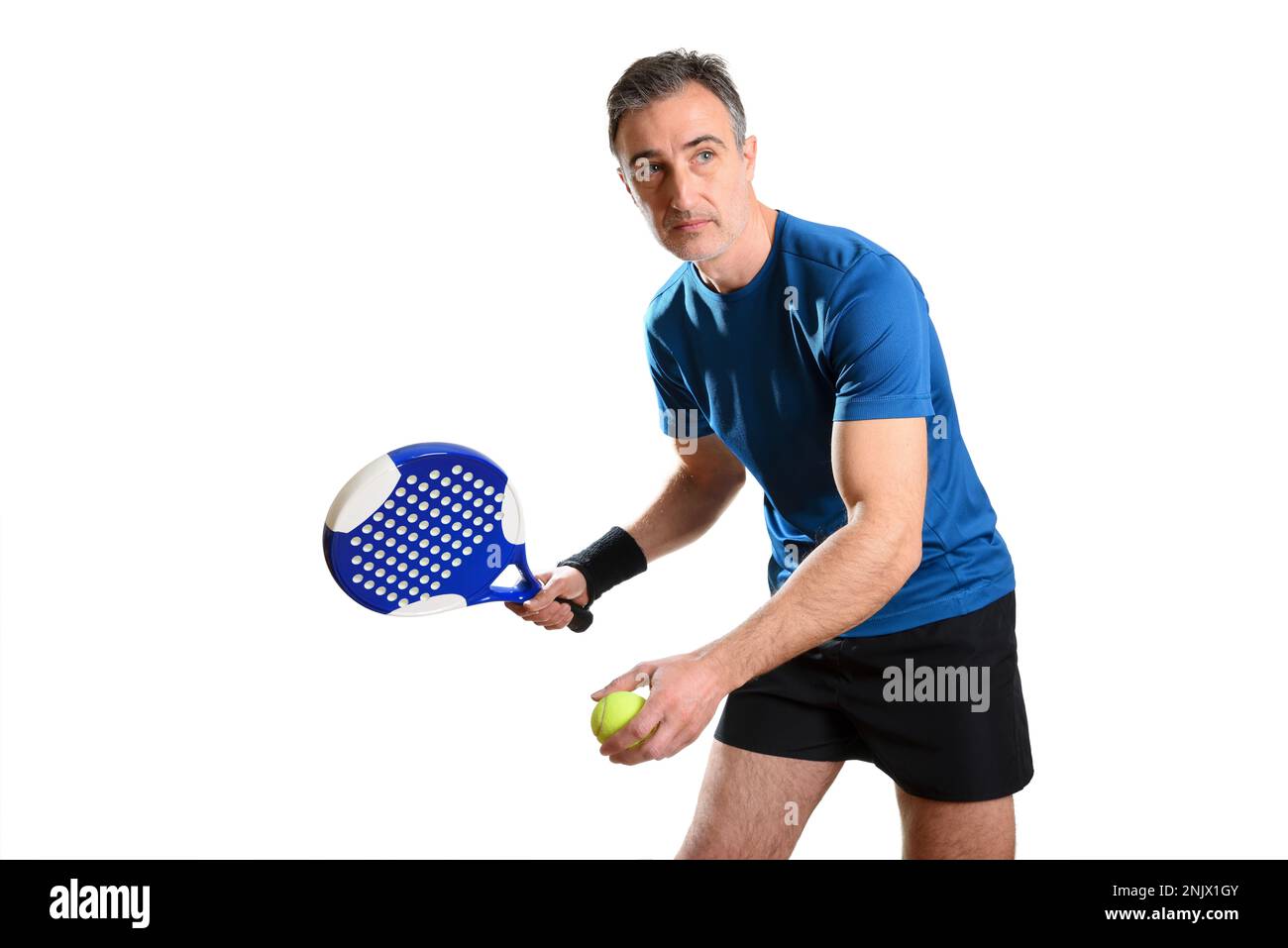 Porträt eines Mannes, der Padel in Servierposition spielt, mit Schläger und Ball in den Händen und blau-schwarzem Sportkostüm auf weißem, isoliertem Hintergrund. Front V Stockfoto