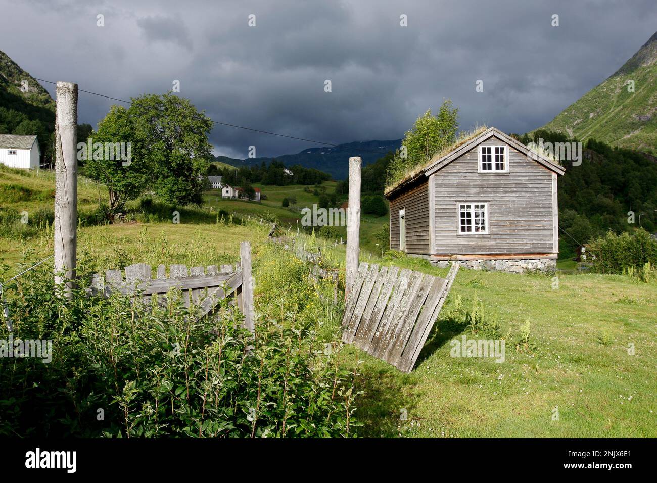 Ältere Holzgebäude an einem Hang. Freiluftmuseum in der Sonne und offene Tore. Berge und Hügel überall. Stockfoto