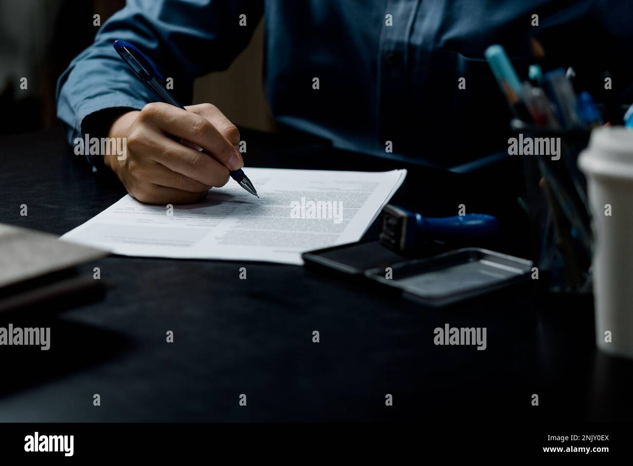 Der Geschäftsmann stimmt zu, am Schreibtisch ein Dokument zur Vertragsunterzeichnung, einen Kaufvertrag oder einen Vertrag über rechtliche Transaktionen zu unterzeichnen Stockfoto