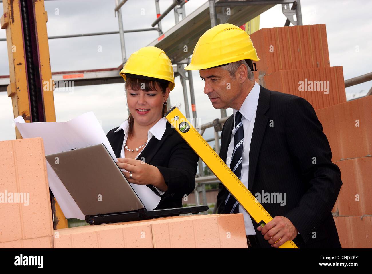 Zwei Architekten mit Laptop, Bauplan und Wasserstand auf der Baustelle Stockfoto