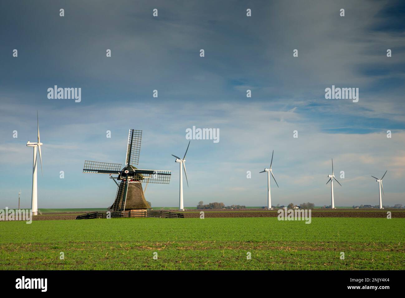 Windmühle zwischen Windrädern am Deich, Niederlande, Frisia, Ferwert Stockfoto