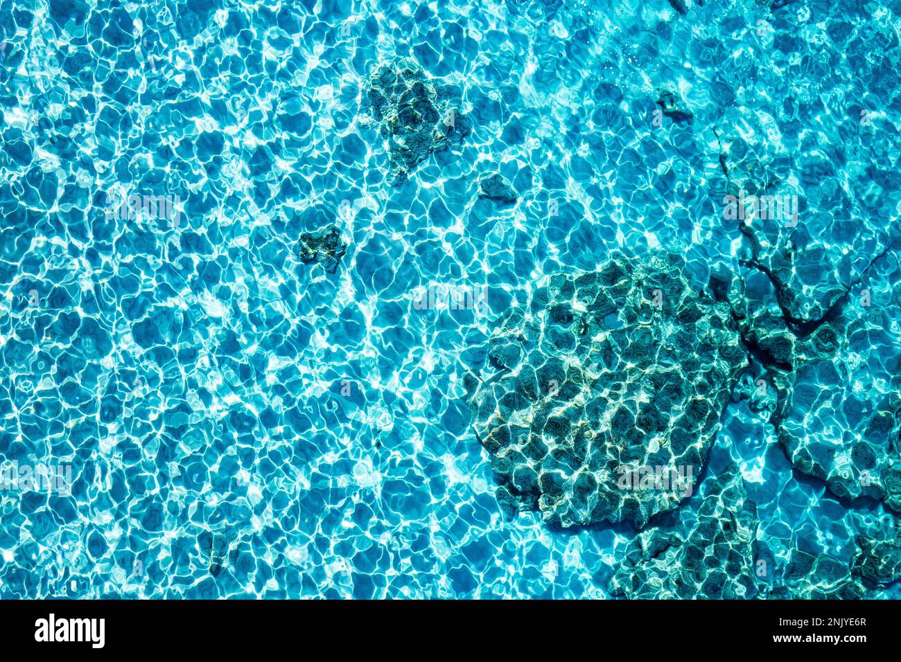 Strukturierter Hintergrund mit türkisfarbener, klarem Wasser am Strand von Cala Turqueta Stockfoto