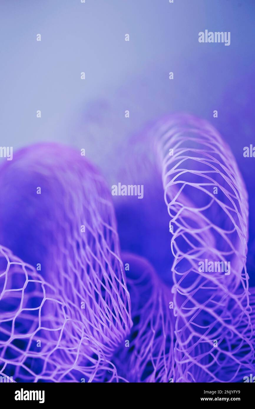 Nahaufnahme des Hintergrunds einer hellvioletten Netztextur mit vielen Löchern vor unscharfem Hintergrund Stockfoto