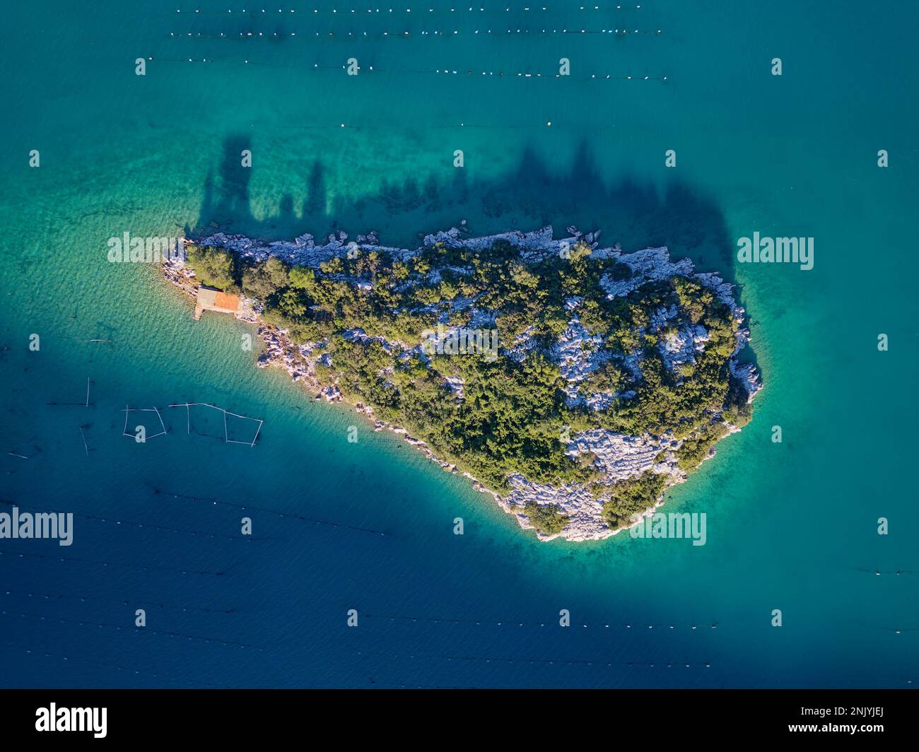 Luftaufnahme einer kleinen Insel in der Bucht von Mali Ston auf der Halbinsel Peljesac. Austernfarmen im türkisfarbenen Meerwasser. Stockfoto