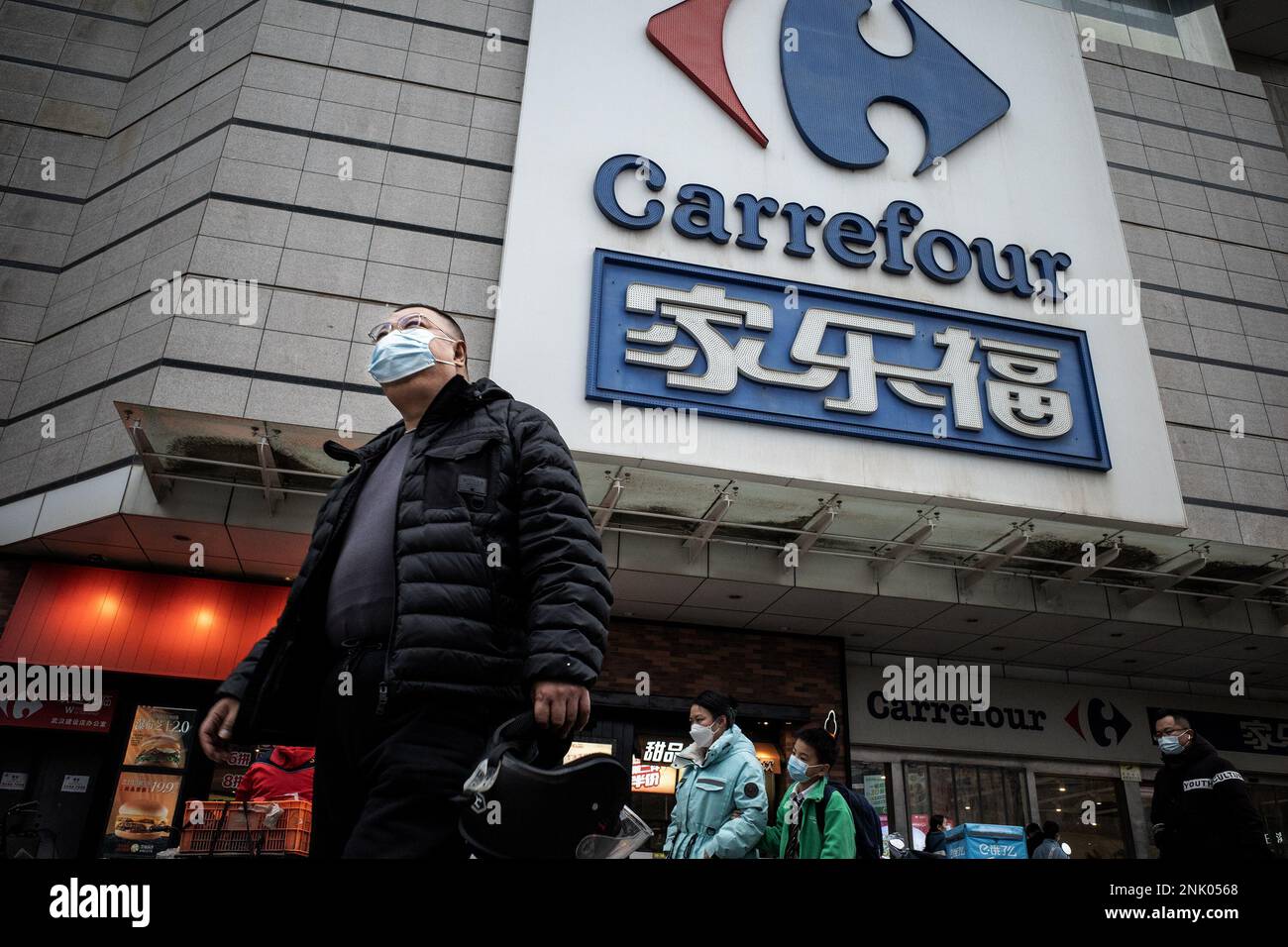 Ein Bürger geht an einem riesigen Schild von Carrefour in Wuhan vorbei. Carrefour trat im Jahr 1995 in den chinesischen Markt ein und expandierte sehr schnell, um einen großen Marktanteil zu sichern. Die Einnahmen nahmen jedoch mit zunehmender Konkurrenz ab. Im Jahr 2019 verkaufte der französische Einzelhändler rund 80 % seines „verlustbringenden“ Geschäftsbereichs in China für 4,8 Mrd. CNY an das in Jiangsu ansässige Unternehmen „Suning“, was zu diesem Zeitpunkt 699 Mio. USD entsprach. In diesem Monat haben Berichte über Engpässe in den zahlreichen lokalen Carrefour-Filialen die Aufmerksamkeit der Kunden erregt. Mehrere Leute begannen sich zu beschweren, dass sie B haben Stockfoto