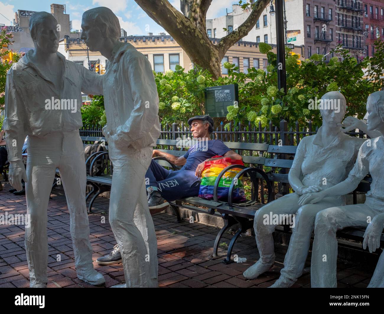 New York City, Vereinigte Staaten - 20. August 2022: Schwulenbefreiungsdenkmal mit einem Mann, der auf einer Bank schläft und einen Regenbogenbeutel hält, ohne andere Leute Stockfoto