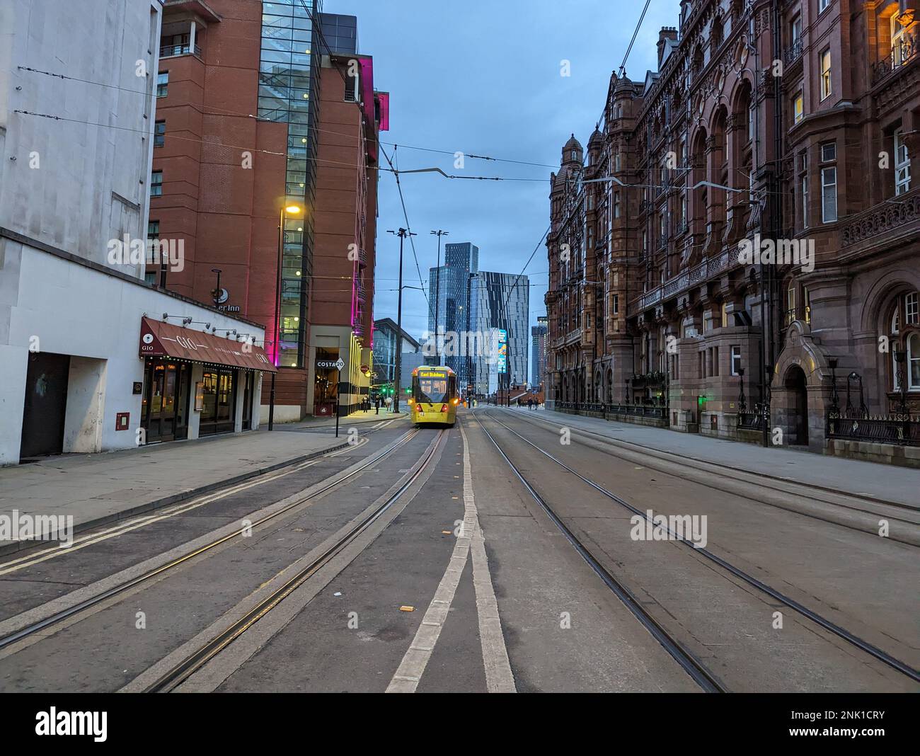 Eine Straßenbahn, die früh am Morgen in Manchester eine leere Straße entlang fährt Stockfoto