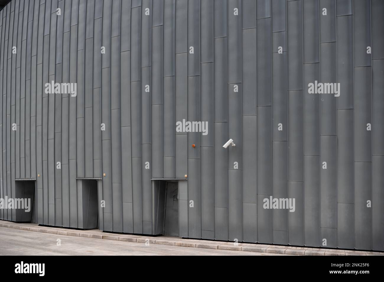 Eine Überwachungskamera über drei Eingangstüren auf einer monotonen Industriefassade Stockfoto