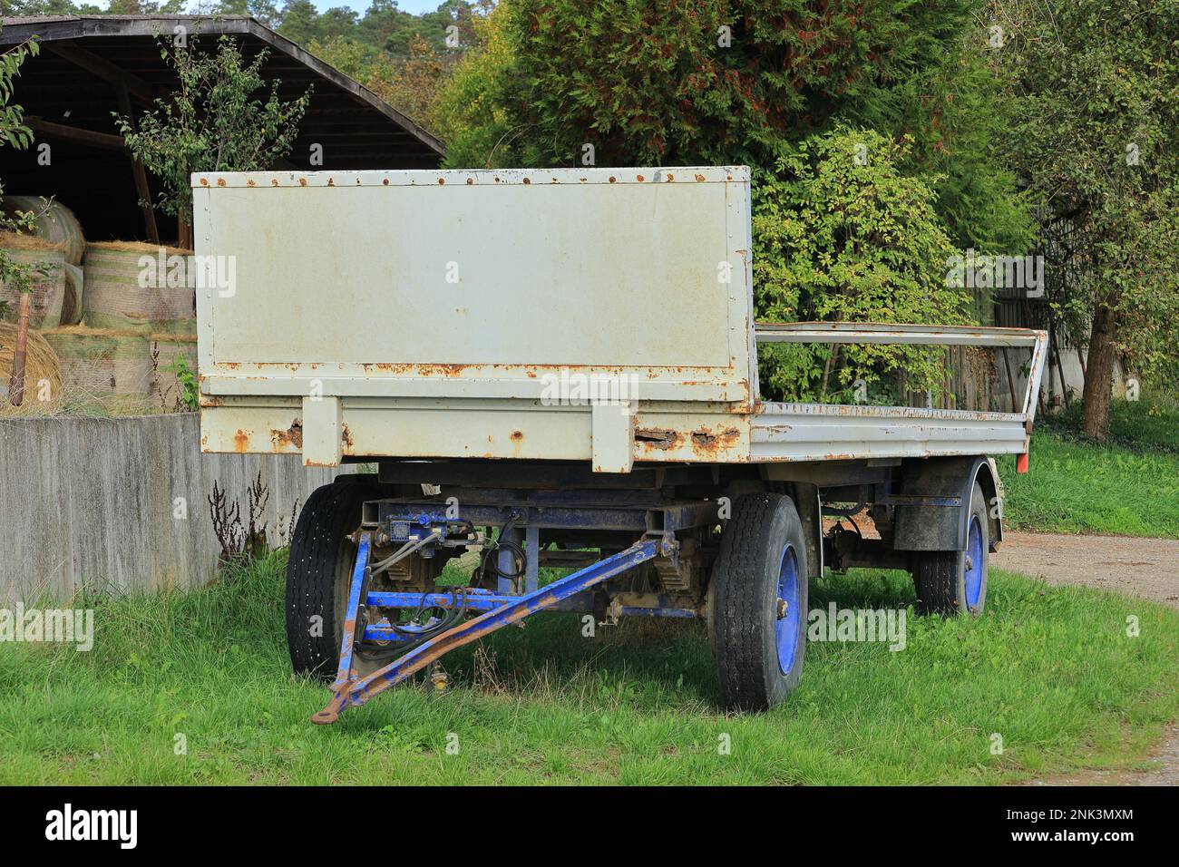 Weißer Anhänger für Heuballen steht auf einer unbefestigten Straße Stockfoto