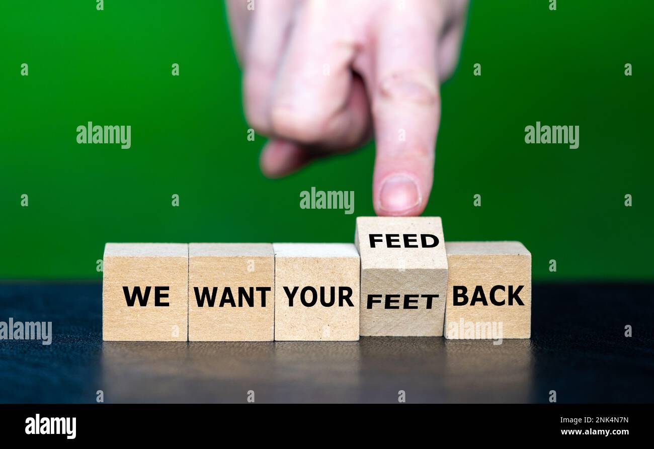 Die Hand dreht den hölzernen Würfel und korrigiert den lustigen Slogan „We want your feet back“ zu „we want your feedback“. Stockfoto