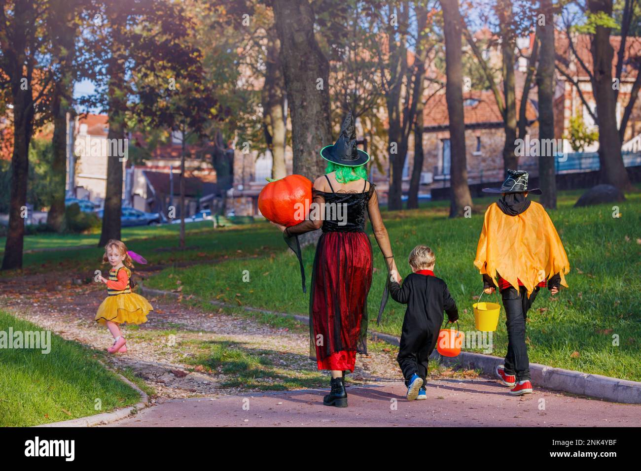 Rückblick auf Mutter, Kinder tragen Halloween-Kostüme, halten Kürbis Stockfoto