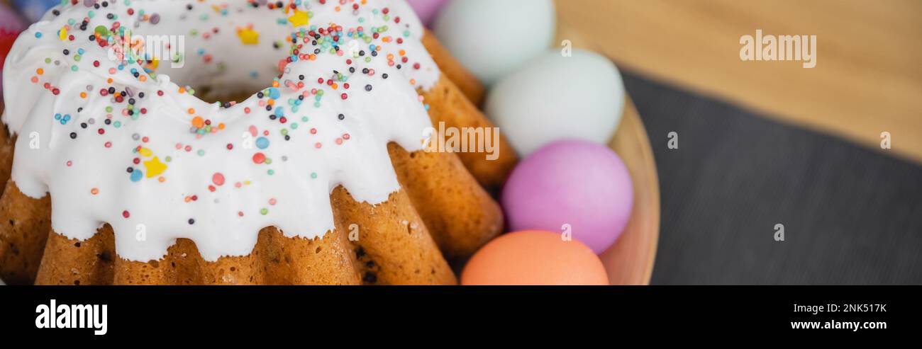 Köstliches Osterbrot und pastellfarbene Eier auf dem Tisch, Banner Stockfoto
