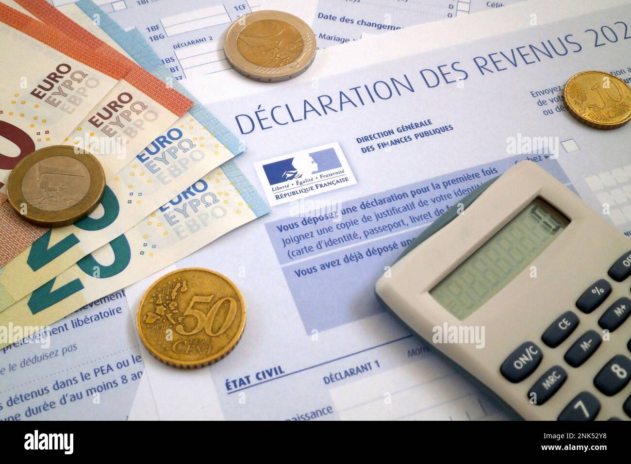 Ein Taschenrechner und einige Euro-Münzen und -Banknoten auf einem französischen Einkommensteuerformular. Stockfoto