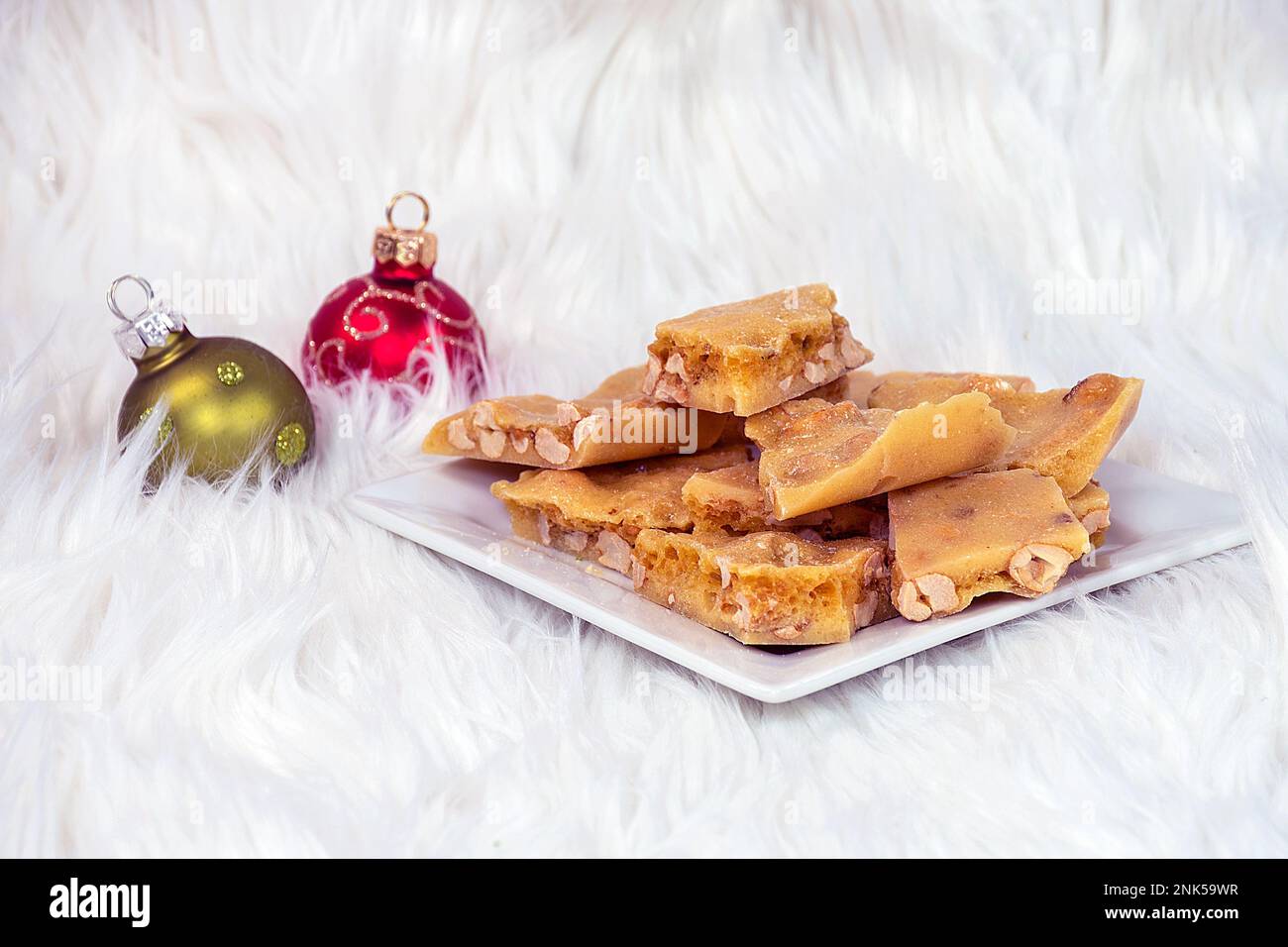 Weihnachtsschmuck in Fell mit Erdnussbrüchig auf weißem quadratischem Teller Stockfoto