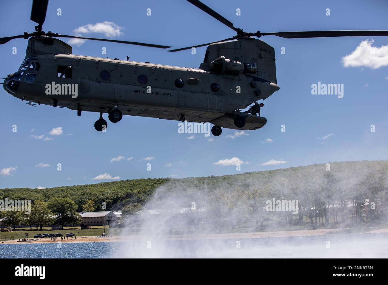 Ein CH-47 Chinook, der dem 2. Geschwader, 107. Kavallerie-Regiment, Ohio National Guard, zugeteilt wurde, schwebt über dem Lake Margrethe in Camp Grayling, Michigan, während einer Helocast-Übung für Soldaten, die die 20. Special Forces Group (Airborne) bis zum Northern Strike 22, 11. August 2022, unterstützen. Ein Helocast ist eine Einführmethode, die von Spezialeinsatzkräften verwendet wird, bei der ein Hubschrauber über ein Gewässer fliegt, um ein Boot abzuwerfen, und Soldaten, die herausspringen, zum Boot schwimmen und sich zu ihrem Ziel an Land bewegen. Stockfoto