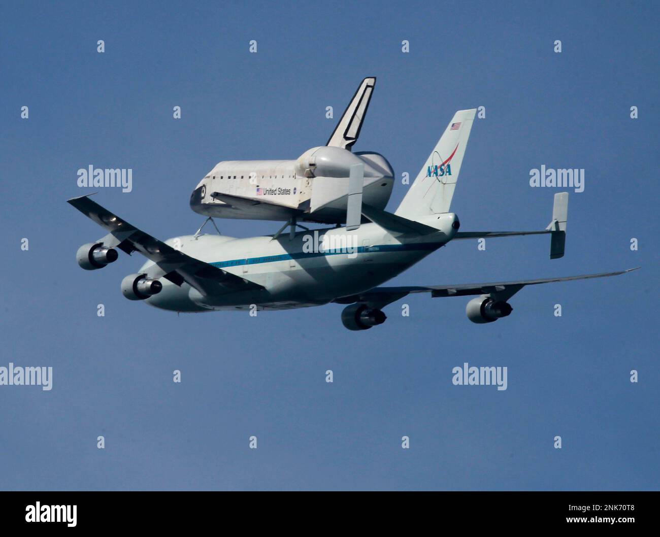 Mounted on top of a NASA transporter, the space shuttle Endeavour flies ...