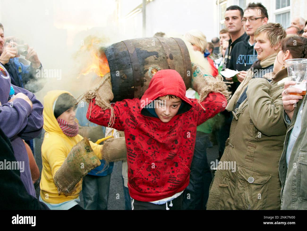 Junger Junge trägt Einen Burning Tar Barrel Ottery St. Mary Devon, Großbritannien Stockfoto