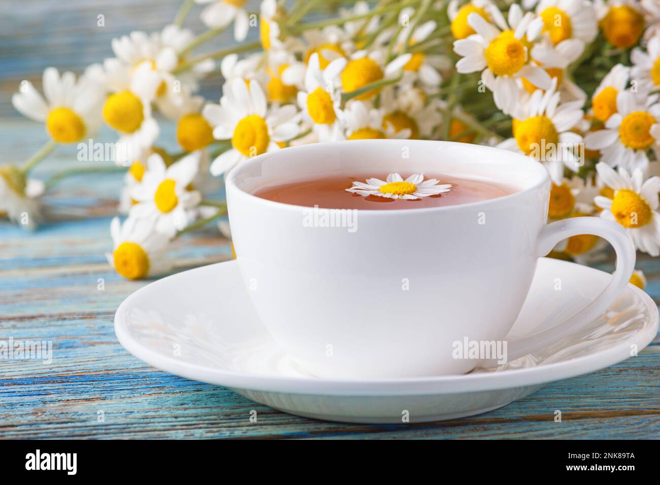 Kamillenblüten für die Teezubereitung und ein Strauß Kamillenblüten aus Matricaria auf Holzhintergrund. Stockfoto