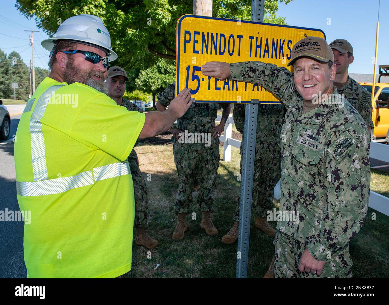 220812-N-PX557-0022 MECHANICSBURG, PA (12. August 2022) Capt. Gene Cash, kommandierender Offizier, Naval Supply Systems Command (NAVSUP) Business Systems Center (BSC) und Tim Reeder, Highway Foreman, Pennsylvania Department of Transportation (PennDOT), aktualisieren ein Highway-Schild auf der Sporting Hill Road, um die 15-jährige Partnerschaft von NAVSUP BSC mit dem Programm widerzuspiegeln. Matrosen und Zivilisten, die der NAVSUP BSC zugeteilt sind, entfernen regelmäßig Müll und Schutt von der 3 km langen Straße in Mechanicsburg. Die Marinekommandos werden aufgefordert, sich mit den lokalen Gemeinschaften in den Bereichen Umwelt und Energie zu vereinen Stockfoto