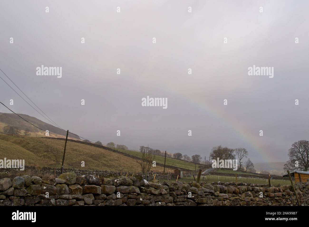 Ein schwacher Regenbogen vor einem grauen Himmel im ländlichen Yorkshire, England. Stockfoto