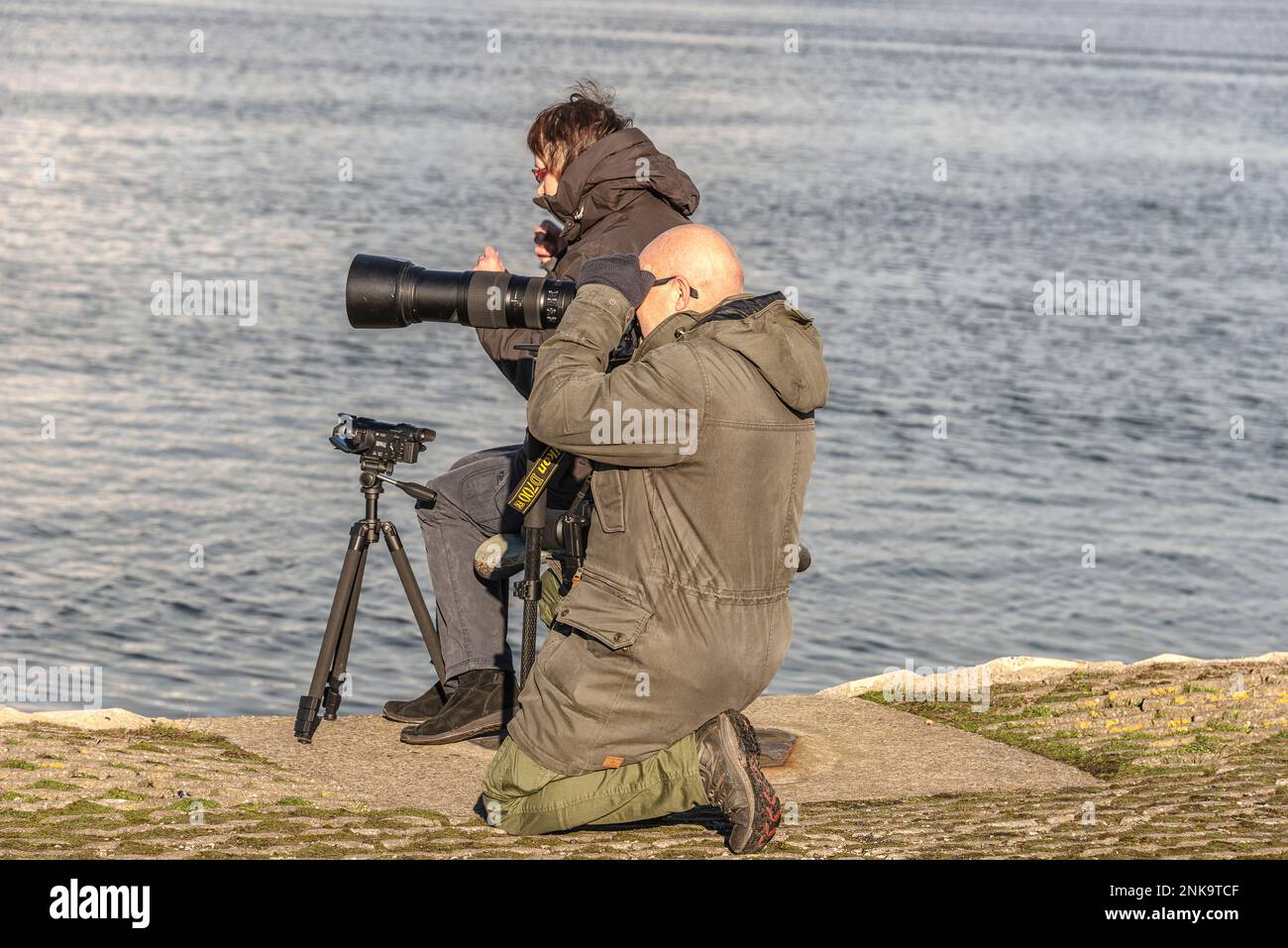 Ein Fotograf mit einem riesigen Teleobjektiv macht Fotos am Nordseekanal in IJmuiden Velsen Niederlande Stockfoto