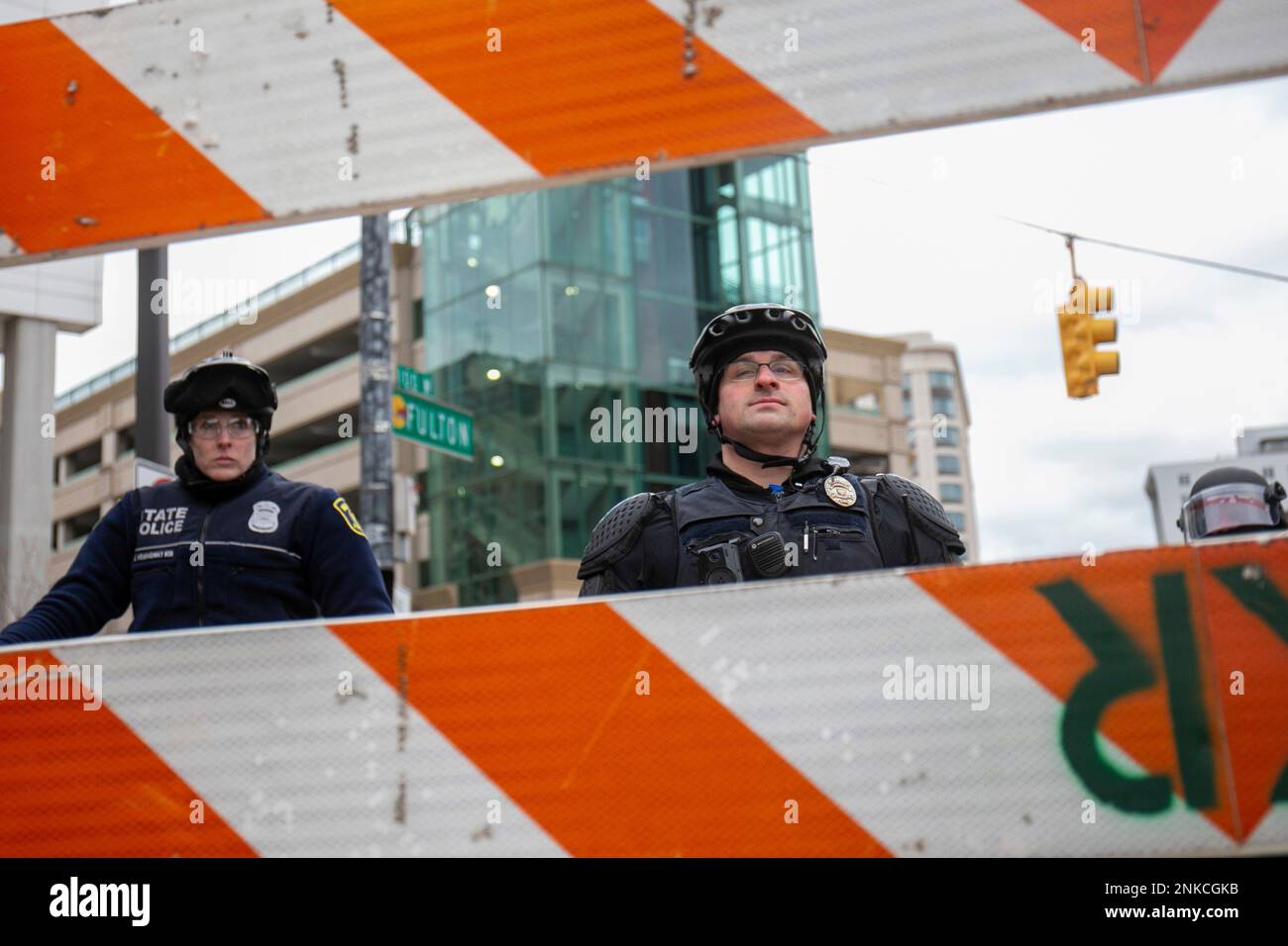 Police officers look towards protesters from behind a barricade in front of the Van Andel Arena in downtown Grand Rapids, Mich., on Saturday, April 16, 2022. Activists have held protests for four straight days since the release of a video showing 26-year-old Congolese immigrant Patrick Lyoya being shot and killed by a Grand Rapids police officer while resisting arrest during a traffic stop on April 4. (Daniel Shular/The Grand Rapids Press via AP) Stockfoto