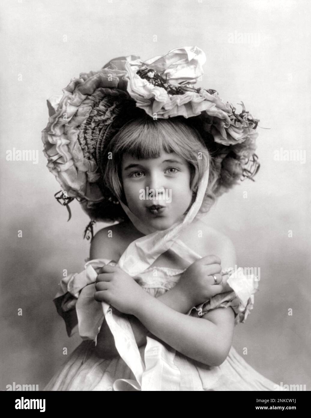 1902, USA: Kleines Mädchen mit Haube. Foto: Fitz W. Guerin . St. Louis, USA - FOTO STORICHE - GESCHICHTE - KIND - BAMBINO - BAMBINI - CUFFIA - HUT - CAPPELLO - BÄNDER - NASTRI - NASTRO - TENEREZZA - ZÄRTLICH - SPITZE - KINDER - BAMBINA - BABY - NOVECENTO - 900 'S - '900 - KINDHEIT - BELLEZZA - SCHÖNHEIT - KISS - BACIO - FRISIERTISCH - FRISIERTISCH - BELLE EPOQUE - ARCHIVIO GBB Stockfoto