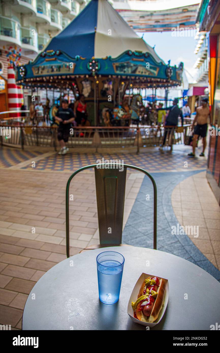 Ein Hotdog und Wasser auf einem Tisch direkt vor dem Karussell auf dem Allure of the Seas, Royal Caribbean Cruise Lines. Stockfoto