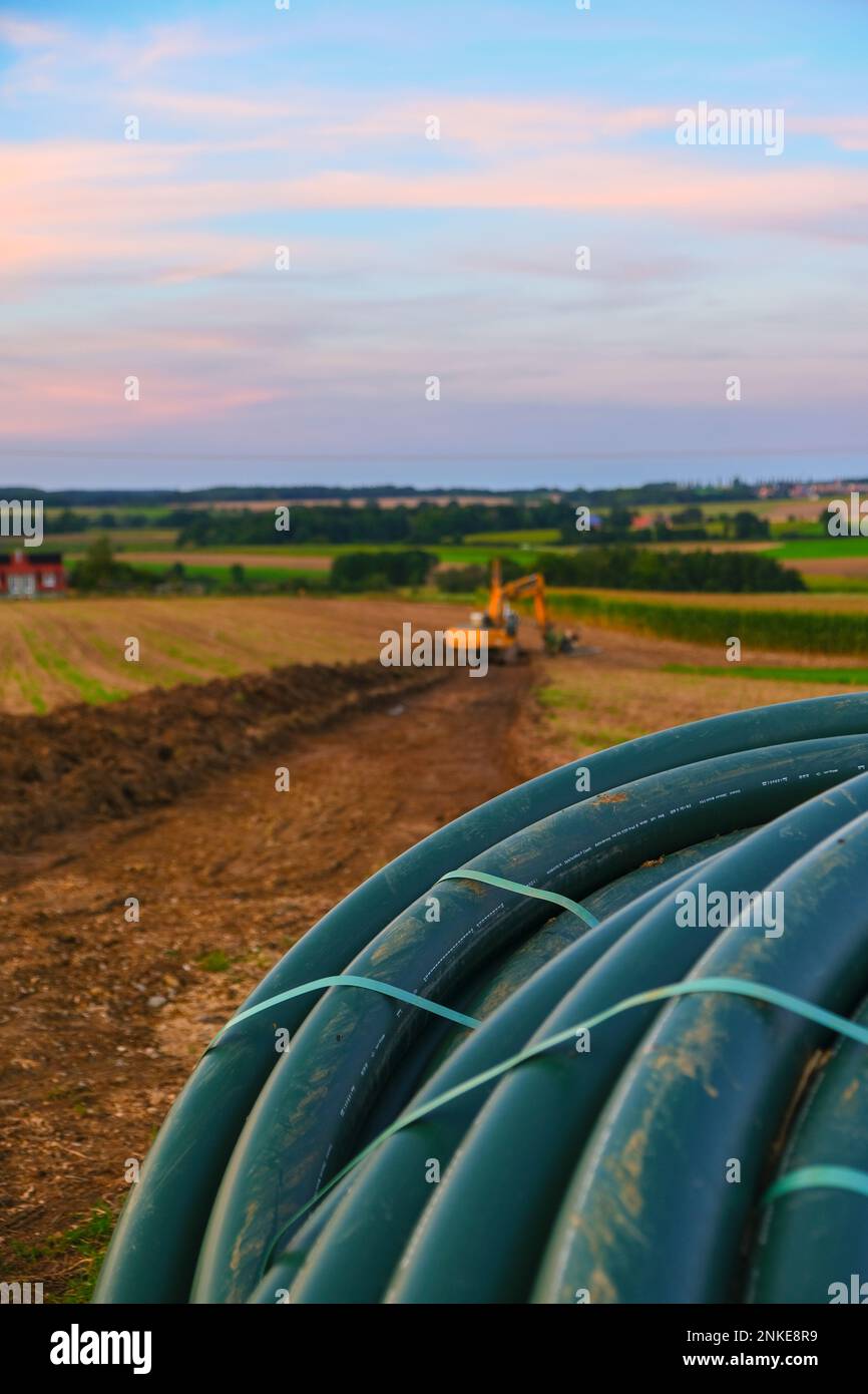 Rohrverlegung. Wasserrohre und gelber Bagger im Feld. Bauarbeiten im ...