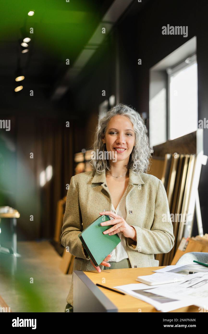 Porträt einer lächelnden Architektin, die im Büro ein Notizbuch hält Stockfoto