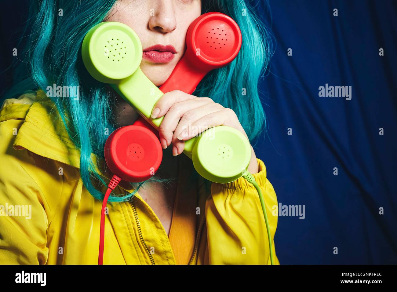 Frau, die grüne und rote Telefonhörer in Kreuzform hält Stockfoto