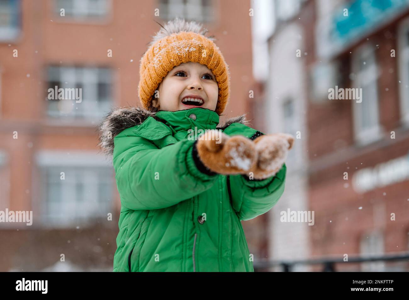 Süßer Junge, der im Winter Schneefall genießt Stockfoto