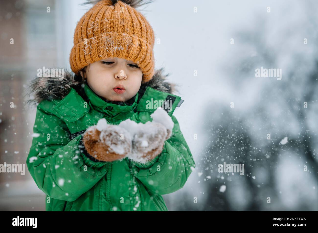Ein Junge, der Schnee bläst und im Winter Spaß hat Stockfoto