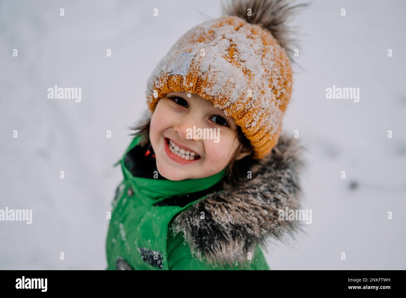 Süßer Junge mit Strickmütze, der im Schnee spielt Stockfoto