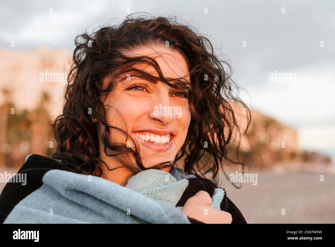 Fröhliche, aufmerksame junge Frau am Strand Stockfoto