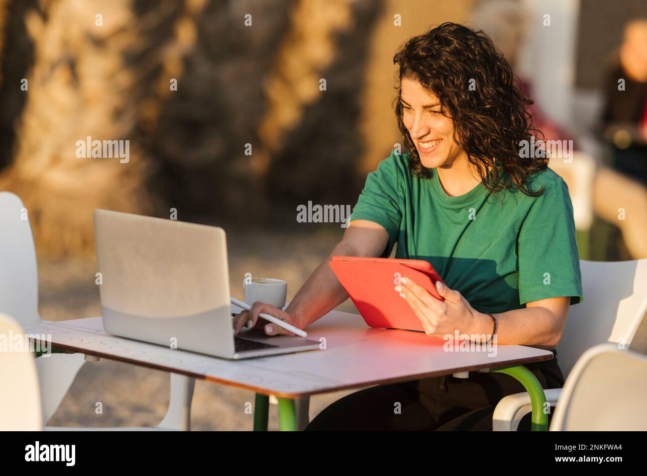 Glückliche Frau, die ihren Laptop benutzt und im Café sitzt Stockfoto