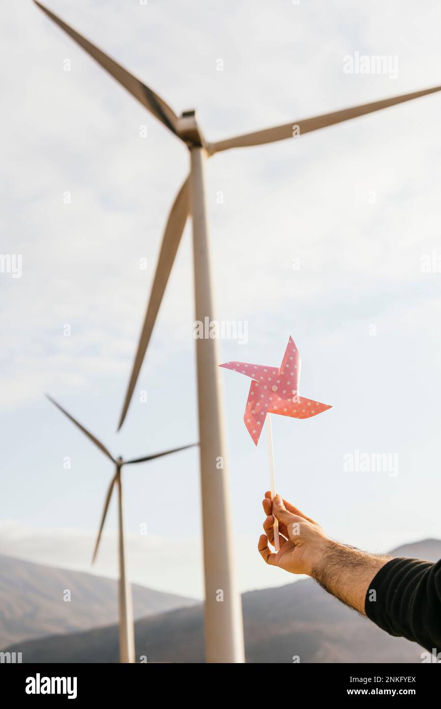 Hand auf Techniker, der das Minirad vor der Windturbine hält Stockfoto