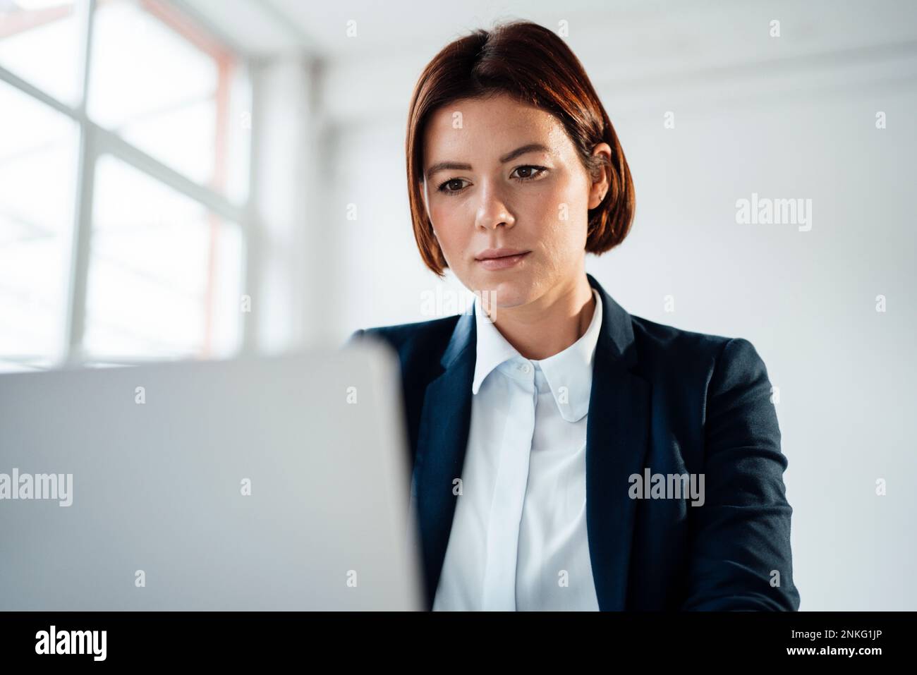 Geschäftsfrau, die am Arbeitsplatz an einem Laptop arbeitet Stockfoto