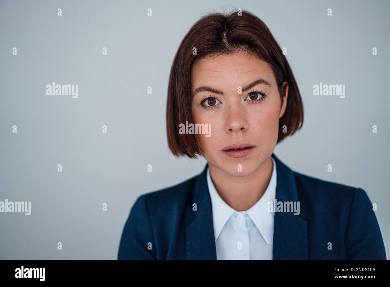 Junge Geschäftsfrau mit kurzen Haaren vor einer grauen Wand Stockfoto