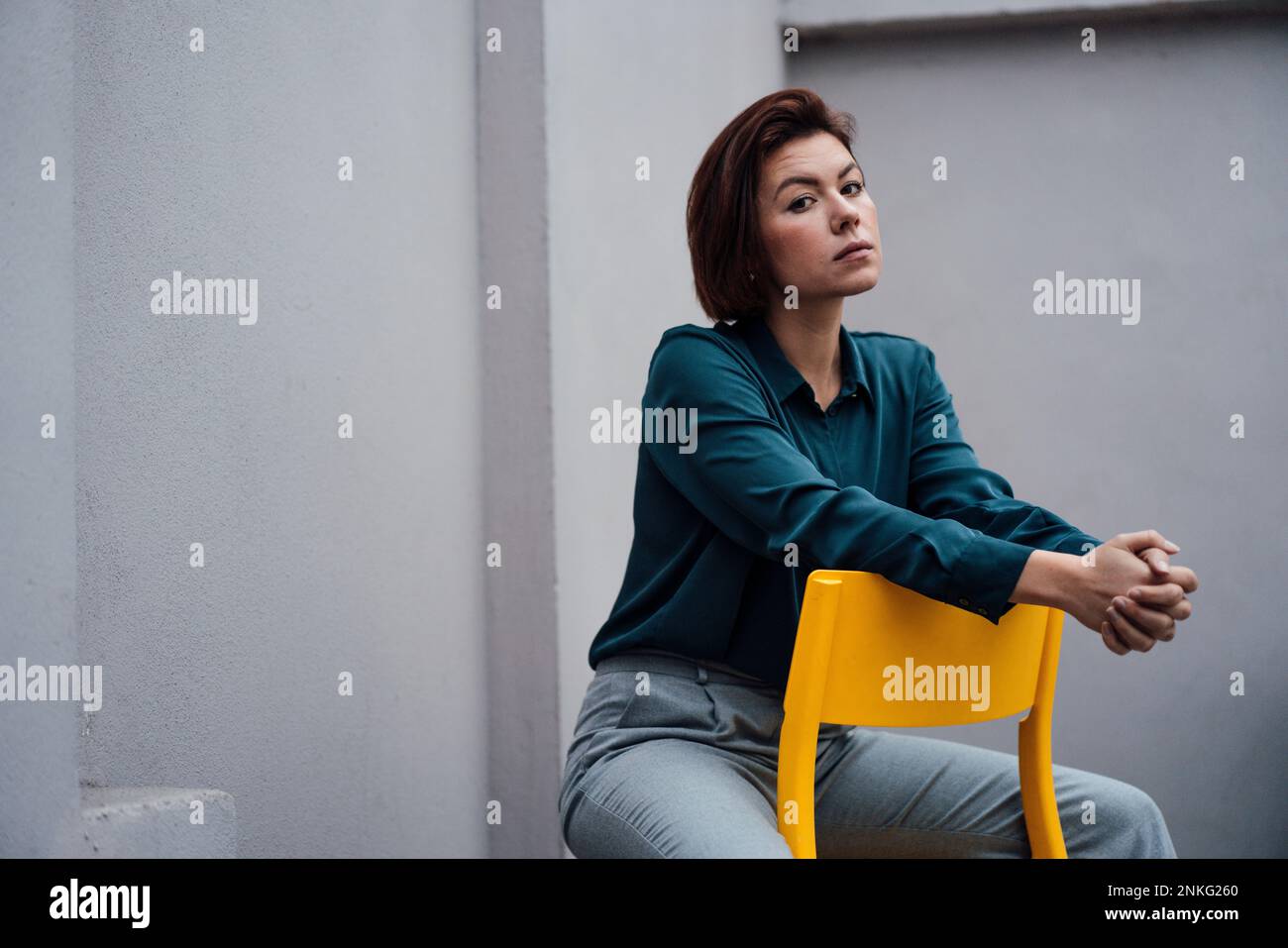Selbstbewusste junge Geschäftsfrau, die auf einem Stuhl sitzt Stockfoto