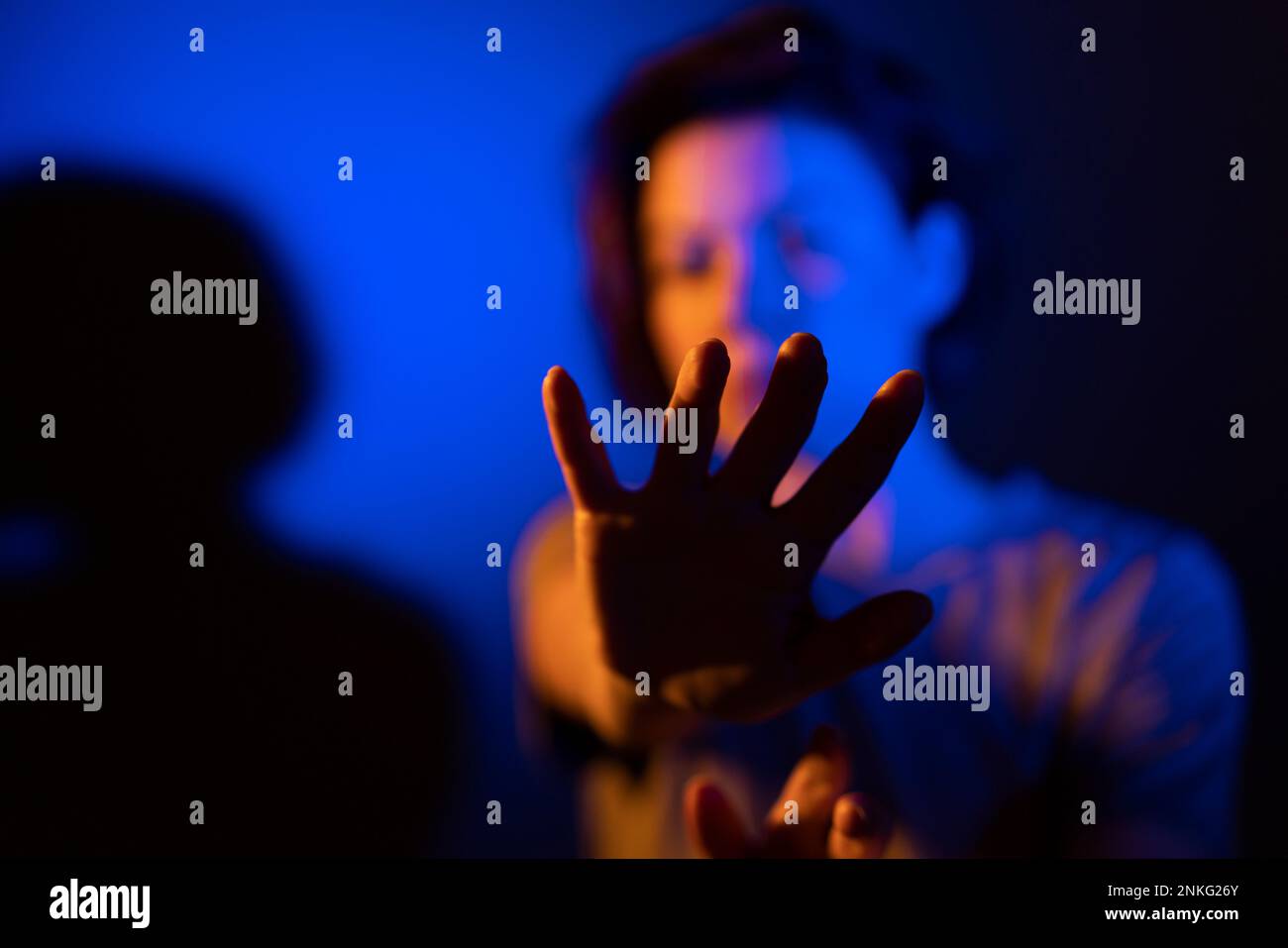 Frau mit Gesten in blauer Neonbeleuchtung vor farbigem Hintergrund Stockfoto
