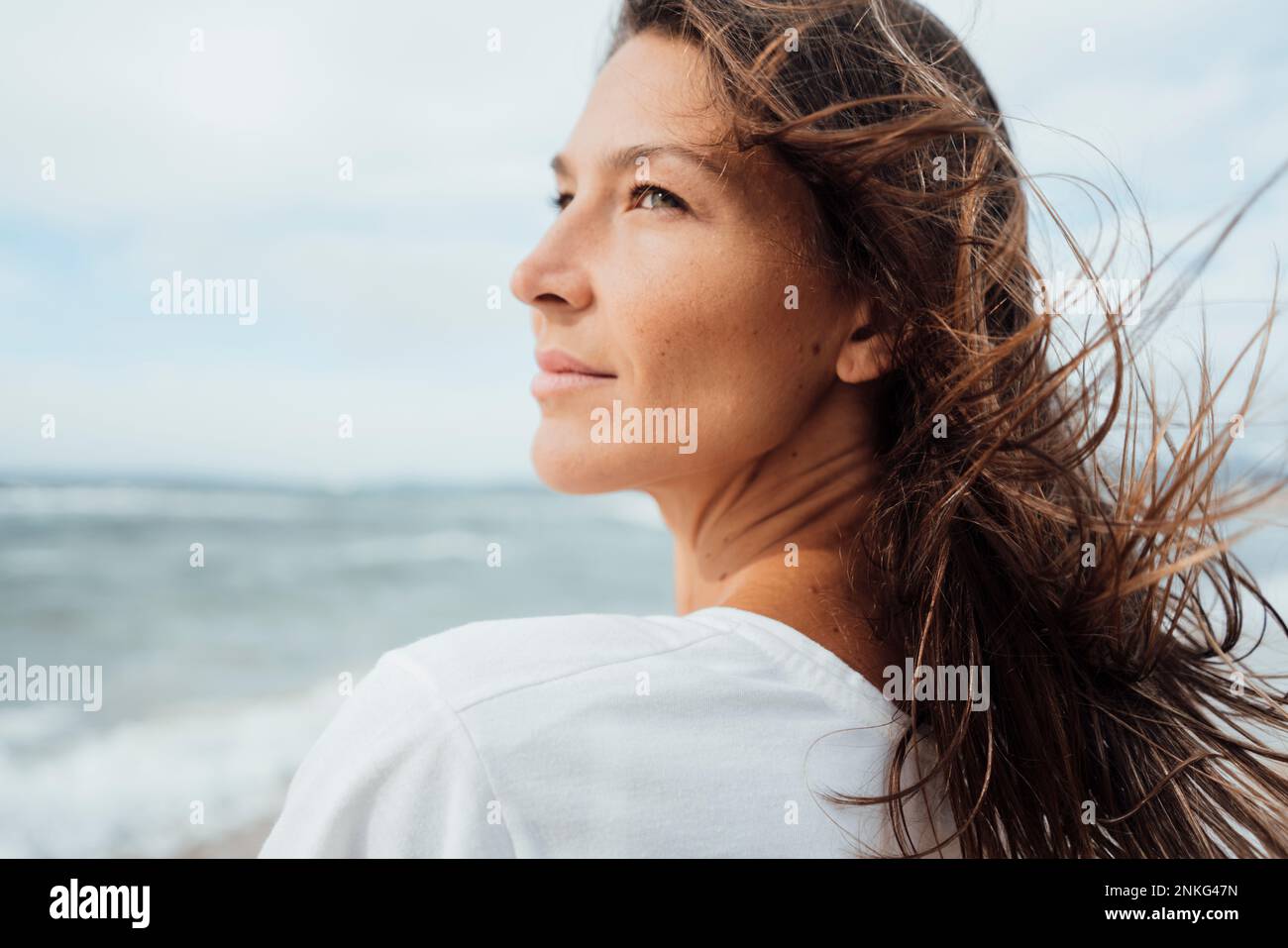 Kontemplative Frau mit langen Haaren am Strand Stockfoto