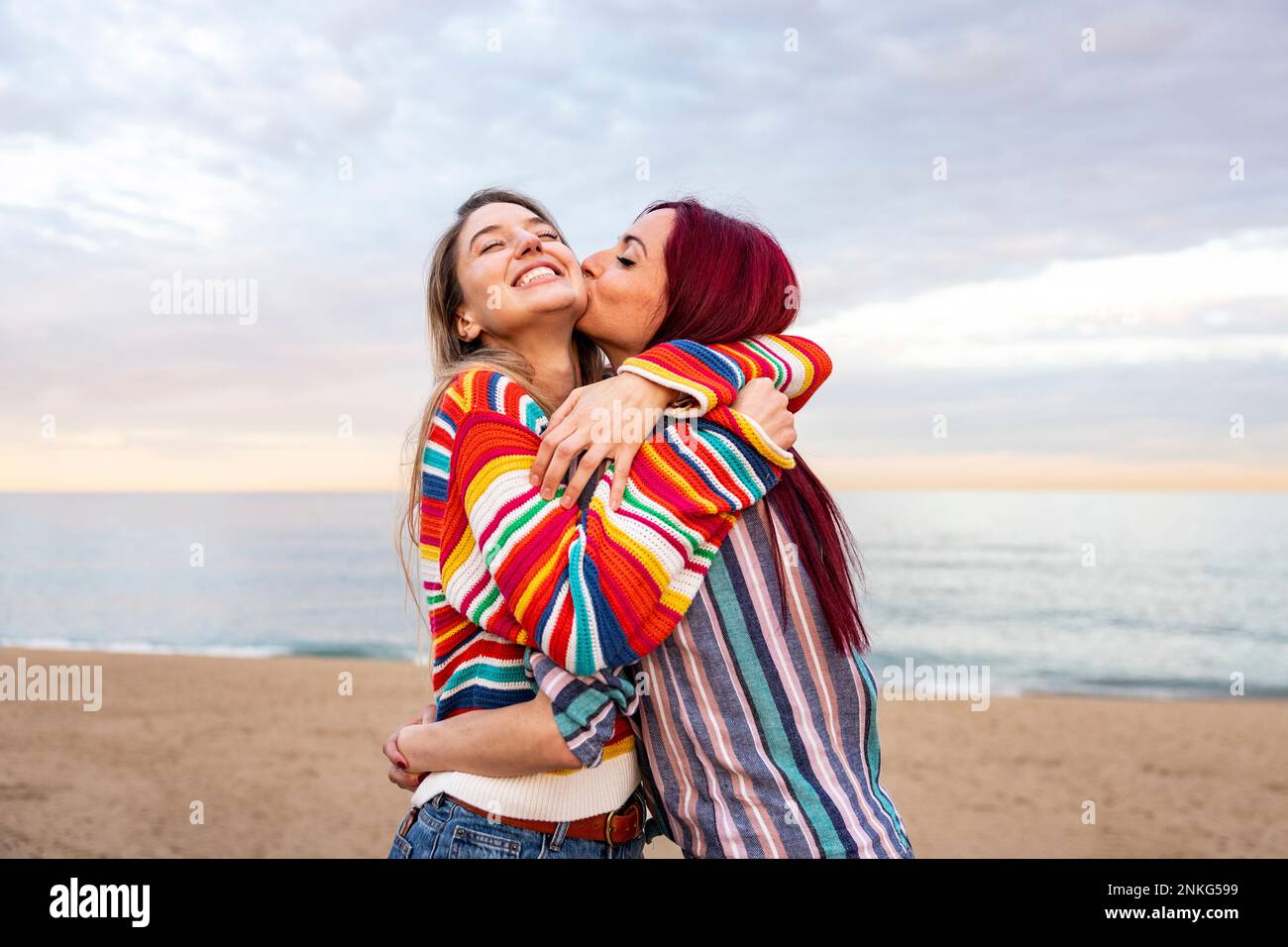 Rothaarige Frau küsst eine Freundin am Strand Stockfoto