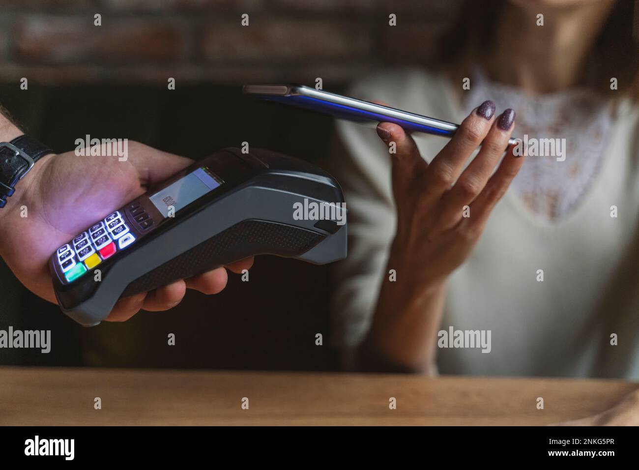 Frau, die im Café per Handy bezahlt Stockfoto